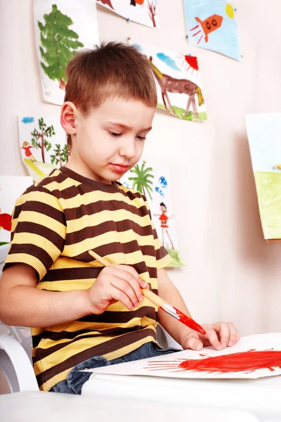 Kleiner Junge mit Pinsel zeichnet rote Sonne im Spielzimmer. — Stockfoto