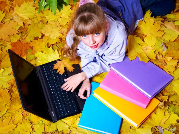 Малюк в осінньому апельсиновому листі з ноутбуком . — стокове фото