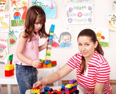 Child with wood block and construction set in play room. clipart