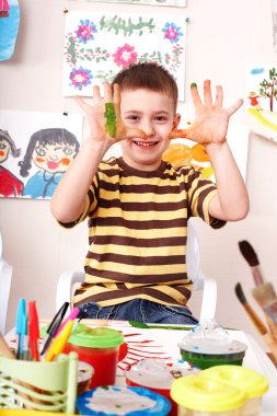 Child with picture and brush in play room. clipart