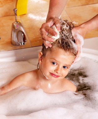 Kid washing hair by shampoo . clipart