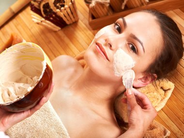 Young woman having clay facial mask. clipart