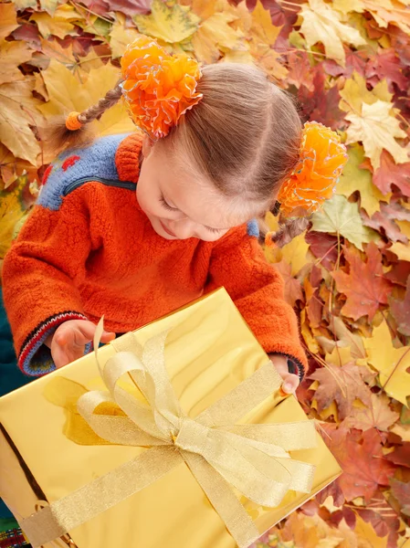 Child in autumn orange leaves and gift box. — Stock Photo, Image