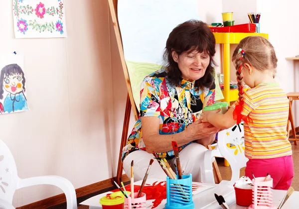 Child with teacher draw paints in playroom. — Stock Photo, Image
