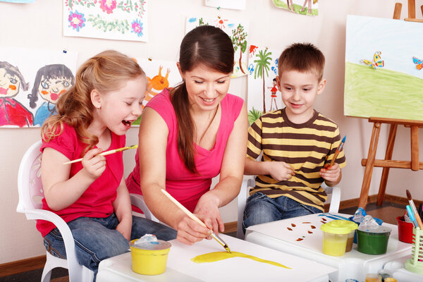 Children with teacher draw paints in play room.