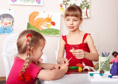 Kids mould plasticine in playroom.