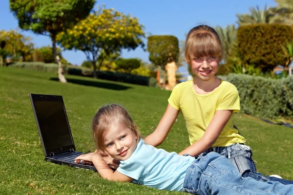 Enfants avec ordinateur portable sur herbe verte . — Photo