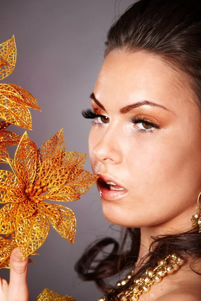 Young woman with gold flower on grey background. — Stock Photo, Image