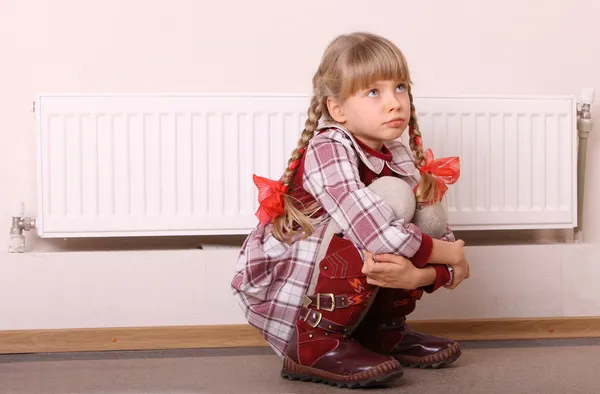 Menina triste sentado perto do aquecedor. Problema das crianças . — Fotografia de Stock