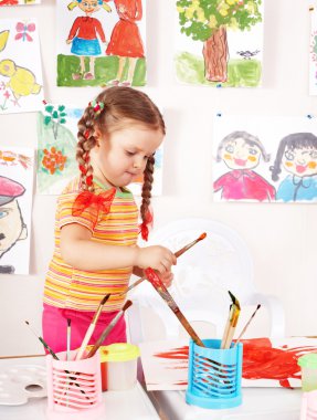 Child paint picture in preschool. clipart