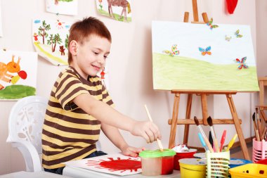 Child paint picture in preschool. clipart