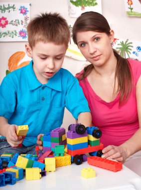 Child playing lego block with mother at home. clipart