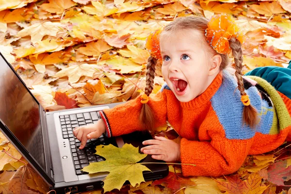 Девочка в осенние оранжевые листья с ноутбуком . — стоковое фото