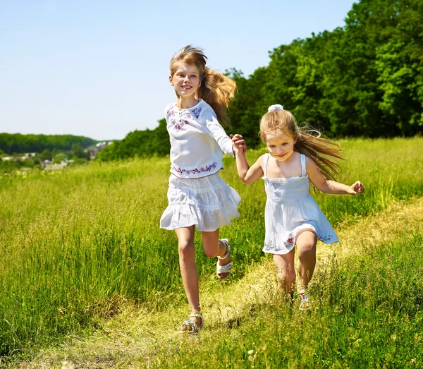 Dzieci biegają po zielonej trawie odkryty. — Zdjęcie stockowe