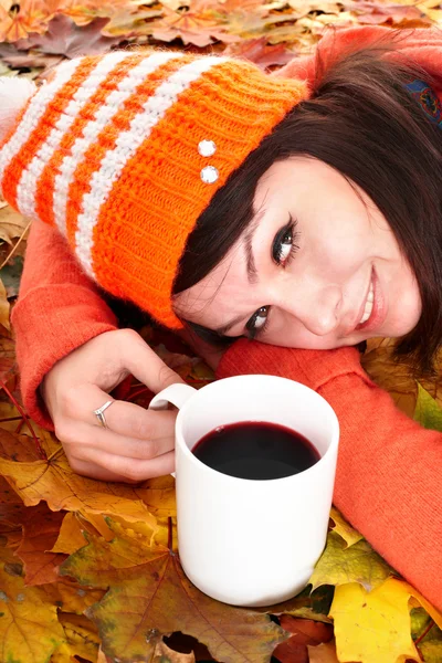 Meisje in herfst oranje bladeren met een kopje koffie. — Stockfoto