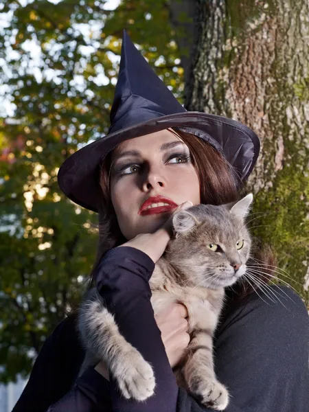 Hexe hält Katze im Freien. — Stockfoto