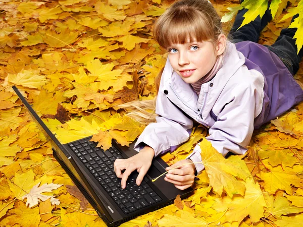 Kid in autumn orange leaves with laptop. — Stock Photo, Image