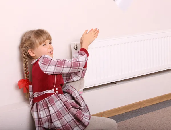 Une fille se réchauffe les mains près du radiateur. Crise . — Photo