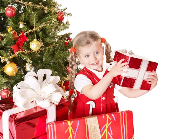Child giving gift box by christmas tree. Stock Image