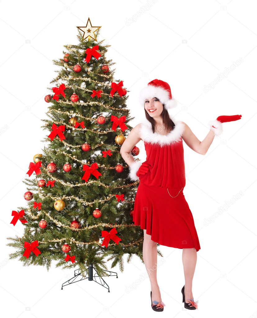 Girl in santa hat by christmas tree.