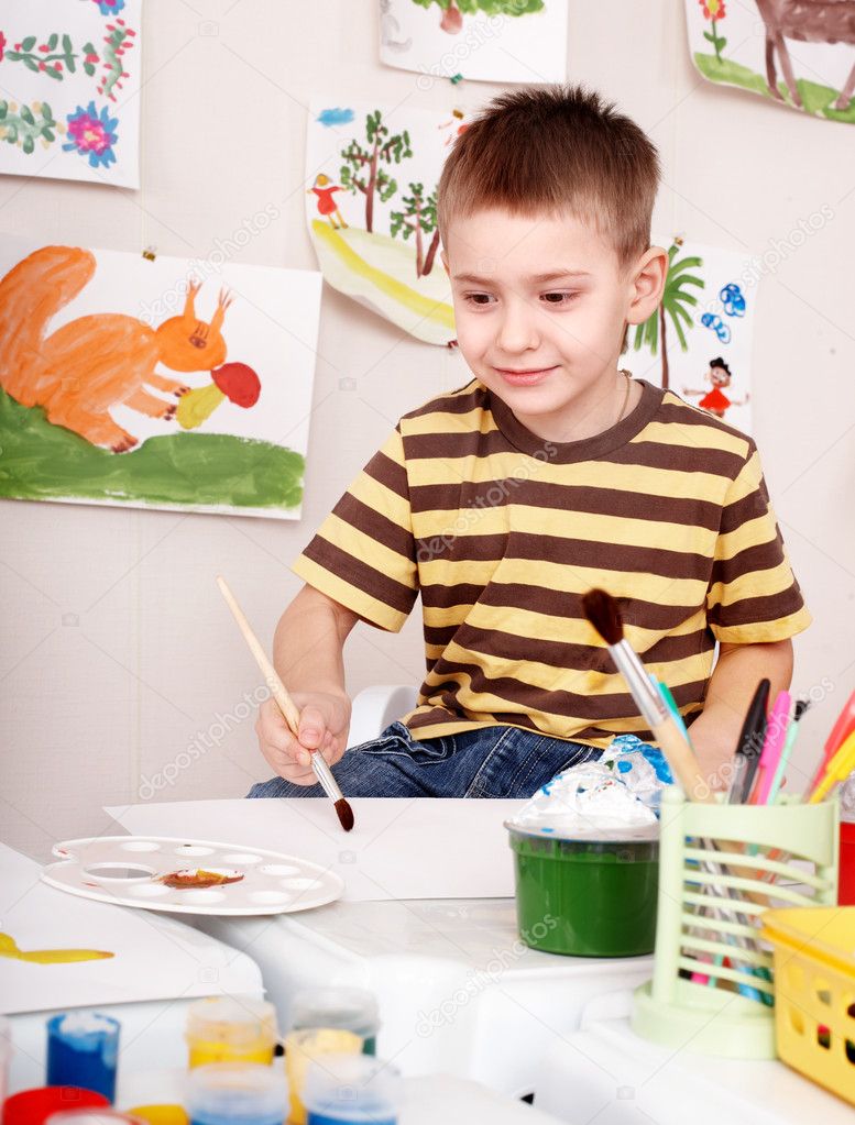 Child with brush draw picture in play room.