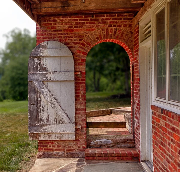 Porta de madeira aberta na parede de tijolo para jardim — Fotografia de Stock