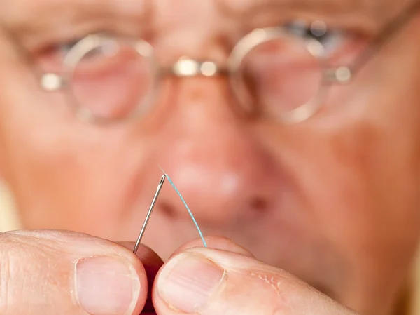 Senior man threading a needle — Stock Photo, Image