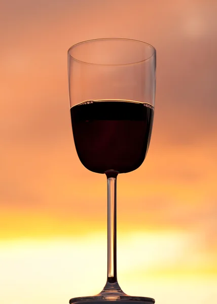 Pôr do sol atrás do copo de vinho tinto — Fotografia de Stock