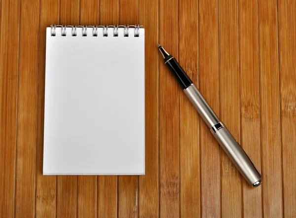 Stift und Notizbuch auf einem Holztisch — Stockfoto