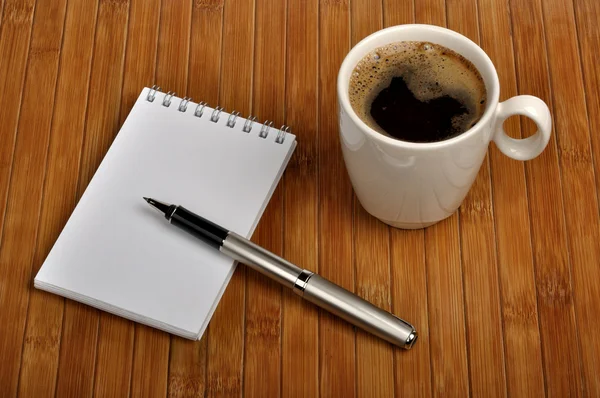 Carnet avec un stylo et une tasse de café — Photo