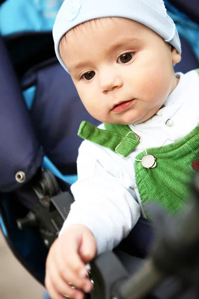 Baby boy sits in blue perambulator. — Stock Photo, Image