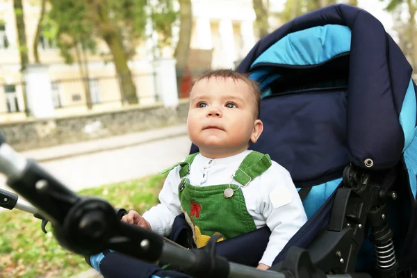 Малыш сидит в синем коляске . — стоковое фото