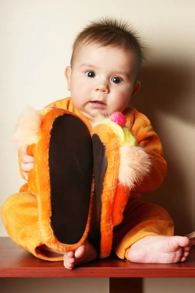 Cute baby boy toddler sitting and holding slippers in hand. — Stock Photo, Image