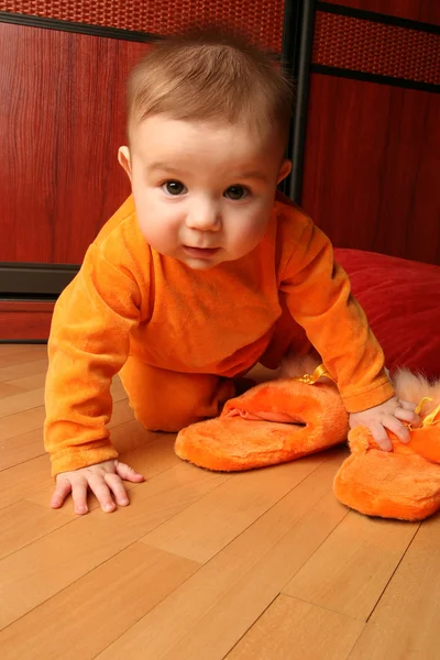 Bébé garçon mignon tout-petit assis et tenant des pantoufles à la main . — Photo