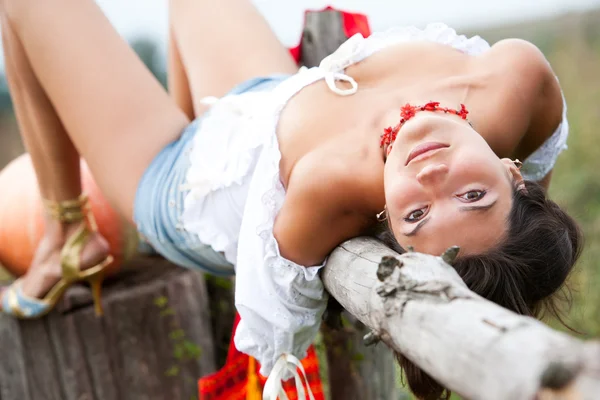 Schöne brünette Frau liegt auf Holzklotz. — Stockfoto
