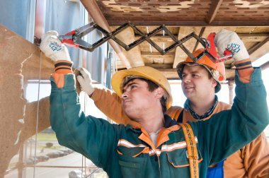 Worker builders at facade tile installation clipart