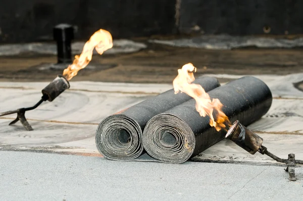 Rouleau de feutre de toiture de goudron et sarbacane avec flamme — Photo