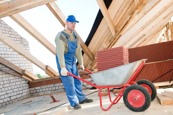 Werknemer dakdekker en wiel barrow met klei tegel — Stockfoto