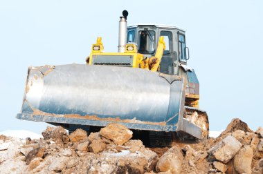 Bulldozer loader at winter frozen soil excavation works clipart