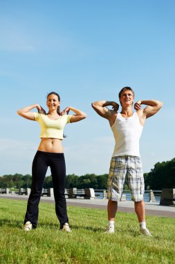 Young man and woman doing stretching exercises clipart