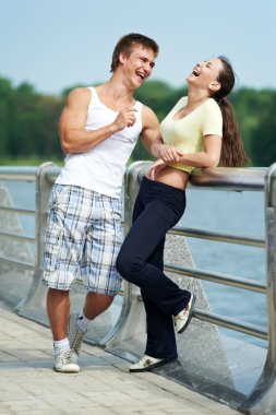 Young man and woman relaxing after jogging clipart