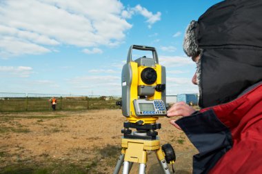 Surveyor works with theodolite tacheometer clipart