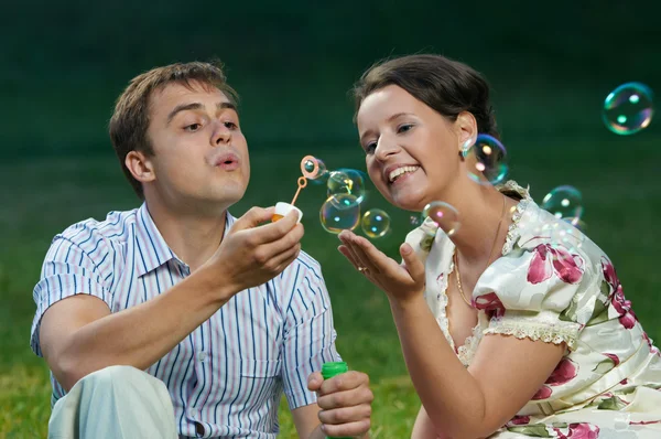 Feliz casal soprando bolhas de sabão — Fotografia de Stock