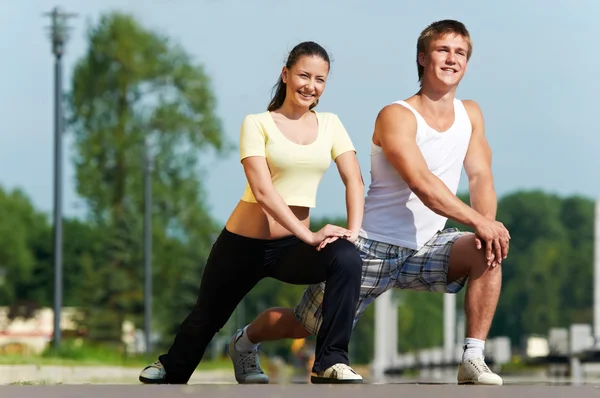Young man and woman doing stretching exercises Stock Photo