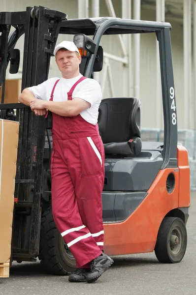 Warehouse worker in front of forklift — Stock Photo, Image