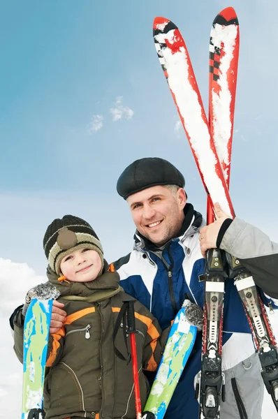 Sonriente hijo y padre con esquís en invierno — Foto de Stock