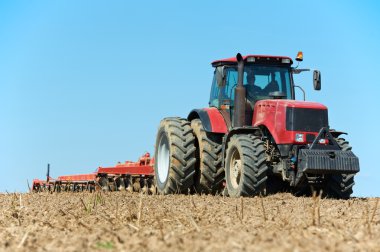 Ploughing tractor at field cultivation work clipart