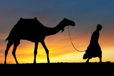 Silhouette of Arab with camel at sunrise clipart