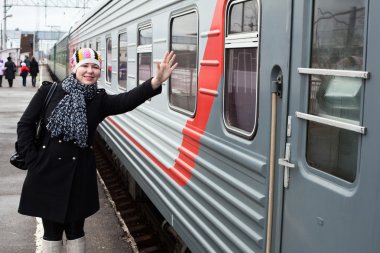 Girl says goodbye departing train and waves by hand after him clipart