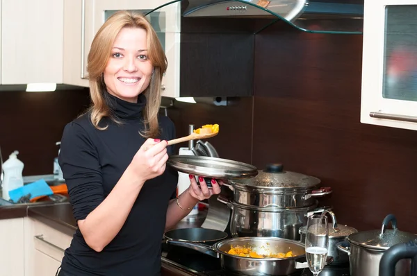 Hermosa mujer feliz sonriente en el interior de la cocina con comida en la sartén . — Foto de Stock